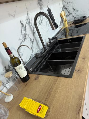 a kitchen counter with a sink and a bottle of wine at Foel Apartament in Tirana