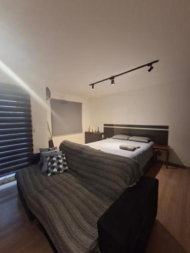 a bedroom with a bed and a couch at Flat 203 Red Sorocaba in Sorocaba