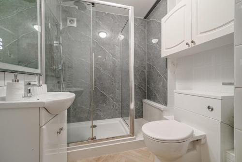 a bathroom with a shower and a toilet and a sink at Fairways - Flat 3 in Weston-super-Mare