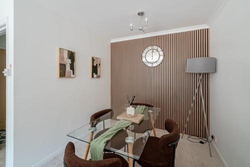 a dining room with a glass table and a clock on a wall at Fairways - Flat 3 in Weston-super-Mare