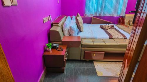 a purple room with a bed and a table at NIGO EXECUTIVE LODGE Mahenge in Mahenge