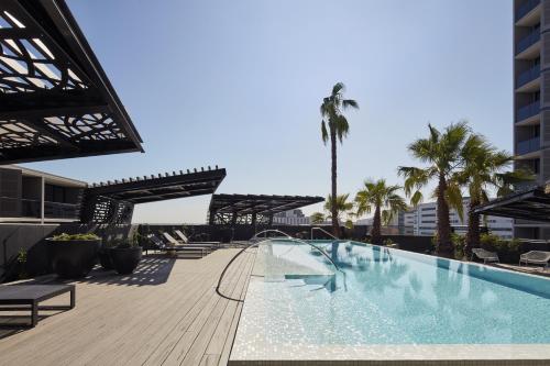 a swimming pool on top of a building with palm trees at Turnkey Accommodation-North Melbourne in Melbourne