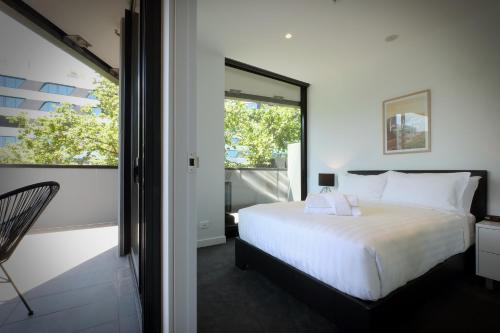 Turnkey Accommodation-North Melbourne في ملبورن: غرفة نوم بسرير ابيض ونافذة