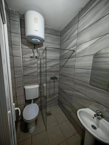 a bathroom with a shower and a toilet and a sink at White apartments in Ulcinj
