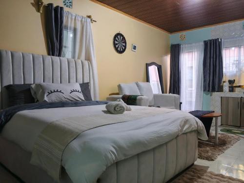 a bedroom with a large bed and a chair at New Era Homes in Kimana