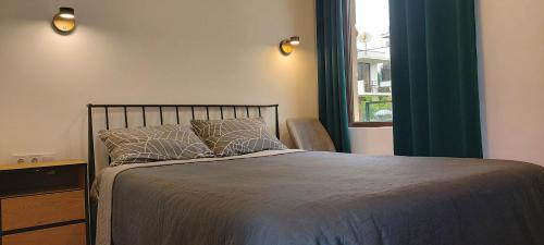 a bedroom with a bed with blue curtains and a window at Apartments Black Pearl of Ureki in Ureki