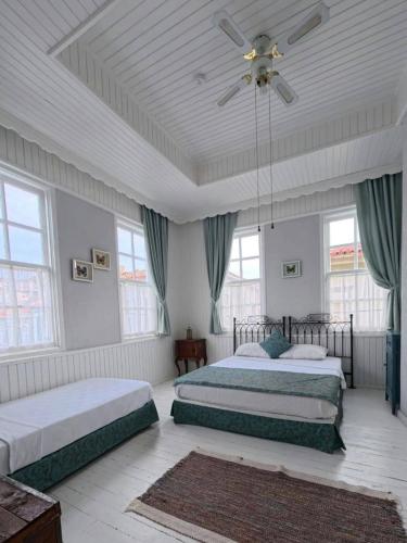 a bedroom with two beds and a ceiling fan at Mimosa House Ayvalık in Ayvalık