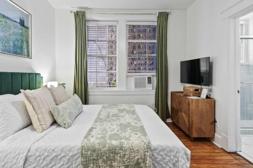 a bedroom with a bed and a flat screen tv at Darling Downtown Renovated Historic Condo Walkable in Savannah