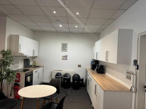 a kitchen with white cabinets and a table and chairs at Zentrales Boardinghouse MG Rheydt in Mönchengladbach