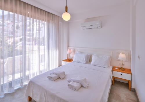 a bedroom with a white bed with two towels on it at Hemera Suite in Kaş
