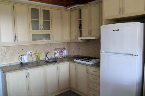 a kitchen with white cabinets and a white refrigerator at Sempati Apart in Mesudiye