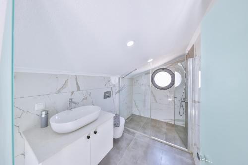 a white bathroom with a sink and a mirror at Hemera Suite in Kaş