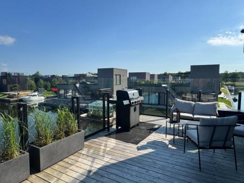 a balcony with a grill and chairs on a roof at Aulaukis in Svencelė