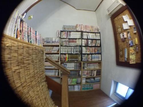 a room with a hallway with book shelves filled with books at Guesthouse Base Okinawa in Naha