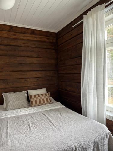 a bedroom with a bed and a wooden wall at Villa Hirsipirtti in Rovaniemi