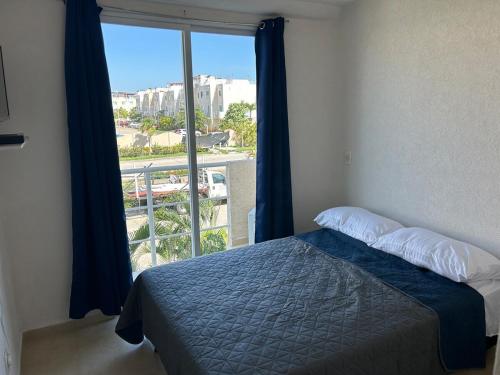 a bedroom with a bed and a large window at Comfortable apartment with pool near beaches in Acapulco