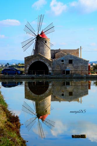 a windmill reflecting in the water with its reflection at Le 5 Torri in Trapani