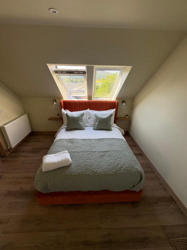a bedroom with a large bed with two windows at Coorie-Tigh in Connel
