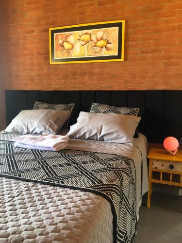a bedroom with a bed with a picture on the wall at Chalé Theo - Para momentos únicos in Camanducaia