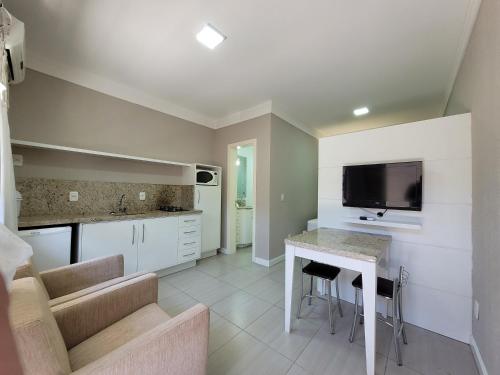 a living room with a kitchen with a table and a tv at MD House Express - Petrópolis in Passo Fundo