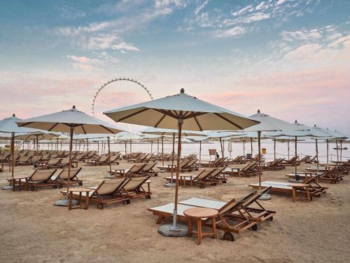 a bunch of chairs and umbrellas on a beach at Rixos Premium Dubai JBR in Dubai