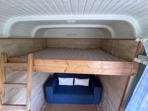 a bunk bed in a tiny house with a blue couch at Genau So - Schäferwagen in Maierhöfen