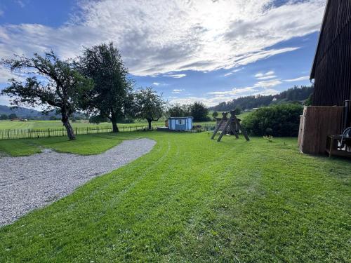 a grassy yard with a tree and a playground at Genau So - Schäferwagen in Maierhöfen