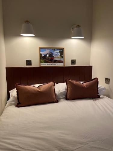a bedroom with a large bed with two brown pillows at Jacobite Cabin in Inverlochy