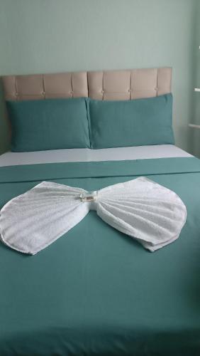 a bed with a white bow tie on it at Pousada Jardim Alameda in Blumenau