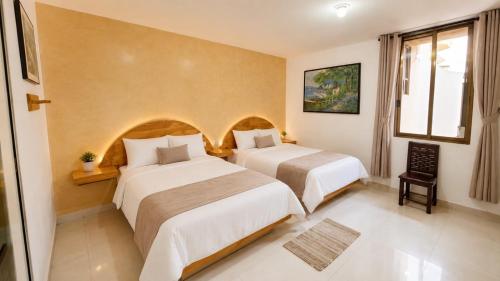 a hotel room with two beds and a window at Hotel Galería Mediterráneo in Santa Ana Huiloac
