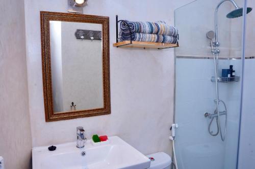 a bathroom with a sink and a mirror and a shower at Dar Halima in Rabat
