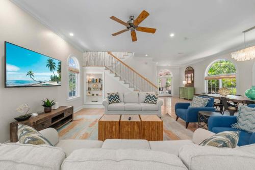 a living room with white furniture and a ceiling fan at Waterfront Pink House with Private Dock & Pool in Captiva