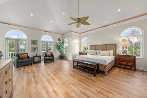 a large bedroom with a bed and a couch and windows at Waterfront Pink House with Private Dock & Pool in Captiva