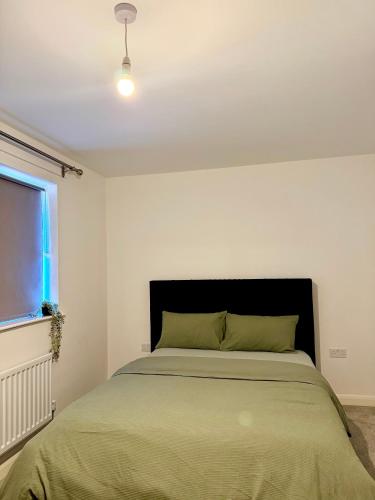 a bedroom with a bed with a black headboard and a window at Classic Foenix Home in Milton Keynes