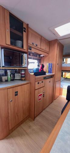 an empty kitchen with wooden cabinets and a kitchen at Ella's Camper in Fontinha