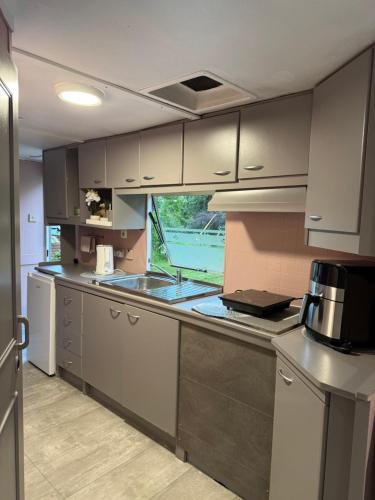 a kitchen with white cabinets and a large window at SeaSoul Cottage in Zvejniekciems