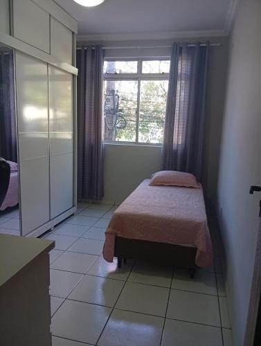 a small bedroom with a bed and a window at Veneza Exclusive 101 in Ipatinga