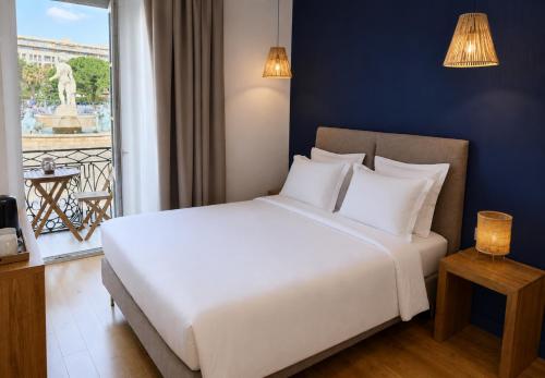a bedroom with a large white bed and a window at Hotel De La Mer in Nice
