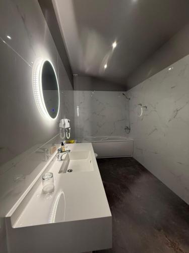 a white bathroom with a sink and a mirror at Fatses in Nea Plagia