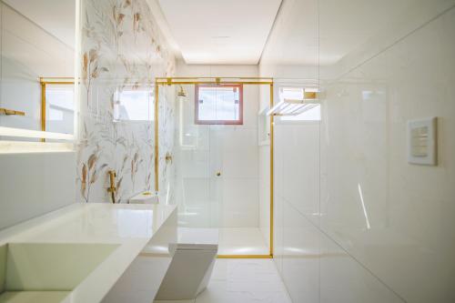 a white bathroom with a shower and a sink at Pousada Recanto dos Chalés in Cruz