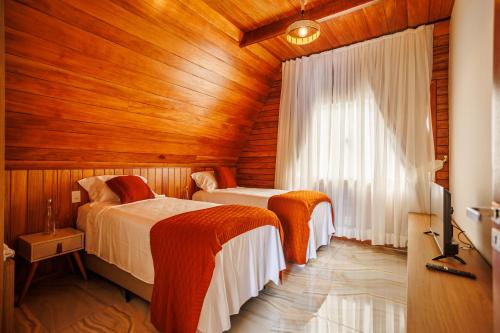 two beds in a room with a wooden ceiling at Pousada Recanto dos Chalés in Cruz