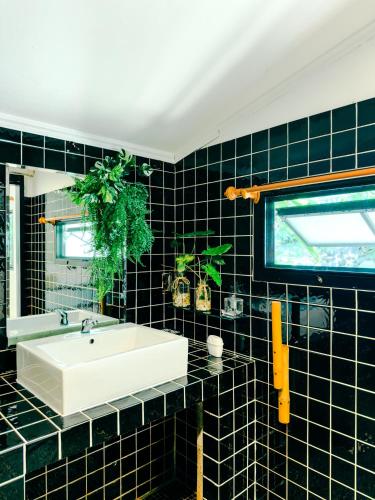 a bathroom with a white sink and black tiles at Watermelon House at Nong Thale Garden & Kitchen in Ban Khao Klom