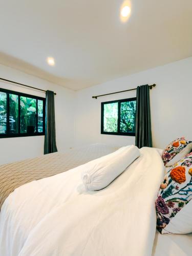 a bedroom with a bed and two windows at Watermelon House at Nong Thale Garden & Kitchen in Ban Khao Klom