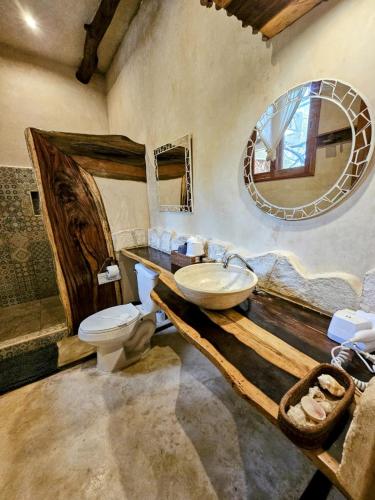 a bathroom with a sink and a toilet and a mirror at La Casa de Mia Holbox in Holbox Island