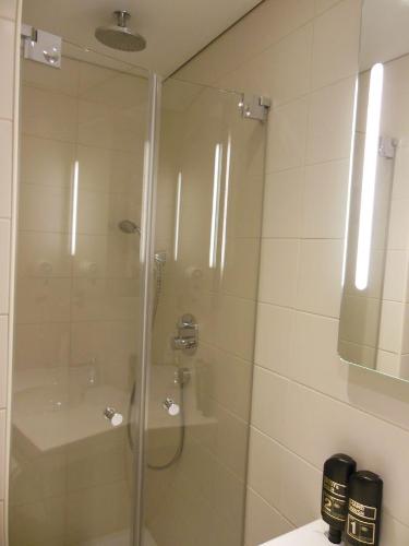 a shower with a glass door in a bathroom at Hotel & Restaurant Zum Ochsen -Ox Distillery in Hösbach