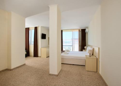 a white bedroom with a bed and a window at La Piazza Primorsko Rooms & Apartments in Primorsko