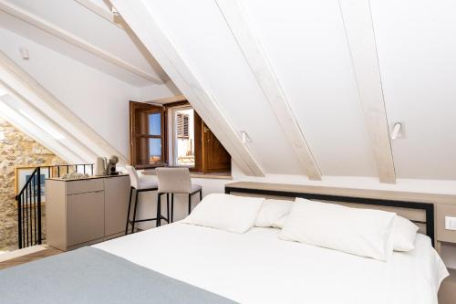Un dormitorio abuhardillado con una cama y una mesa. en Villa Four Winds, en Dubrovnik
