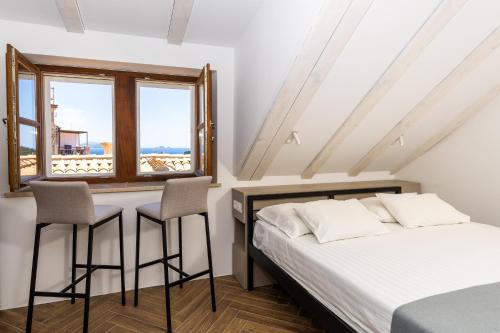 un dormitorio con una cama, dos sillas y una ventana en Villa Four Winds, en Dubrovnik