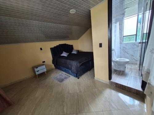 a bedroom with a black bed and a bathroom at Rinconcito campesino in Aquitania
