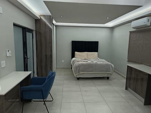 a bedroom with a bed and a blue chair at New Hillcrest centre guest House in Kimberley